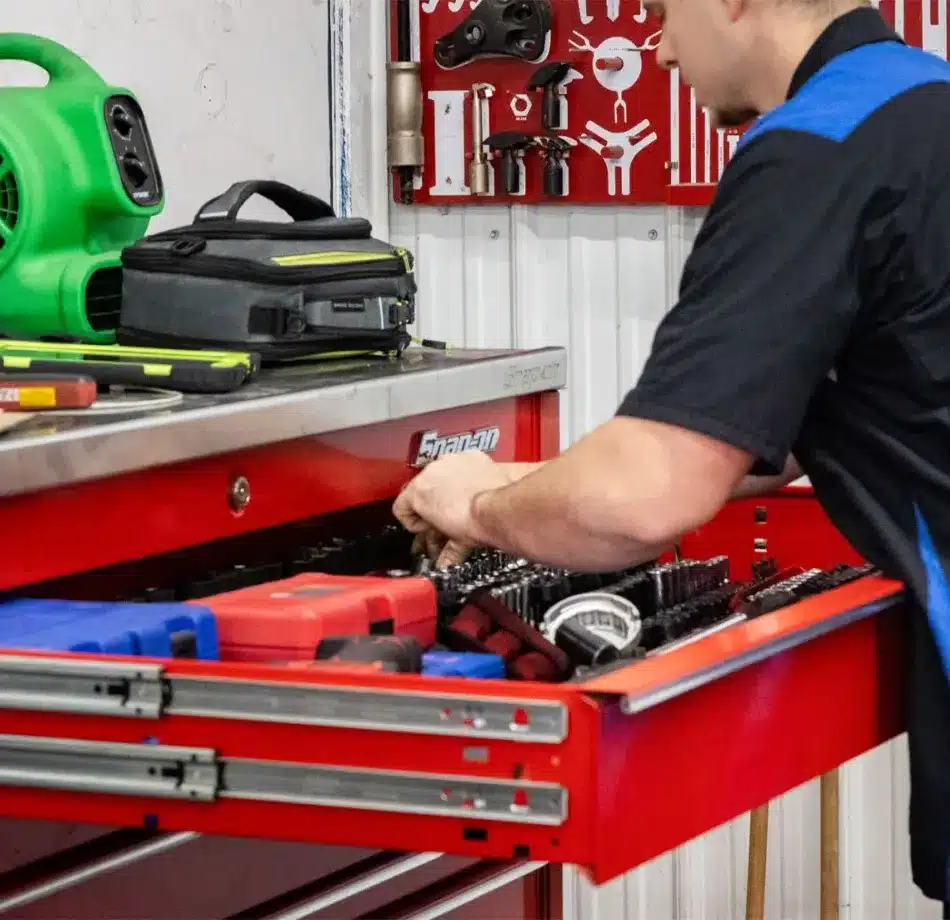Cain and Sonsβ Automotive technician in Glen Rock, PA organizing tools in a red Snap-on tool chest, with tool kits and equipment neatly arranged in the garage.