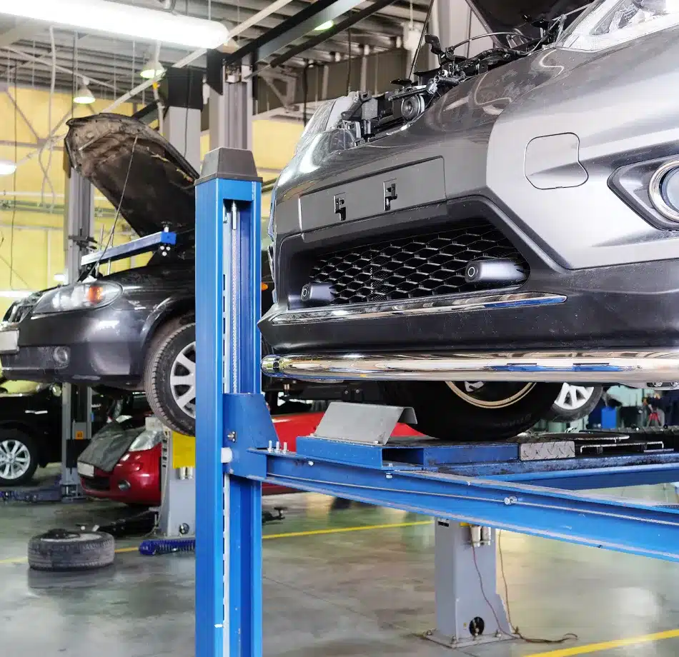 “Domestic vehicle on a hydraulic lift at Cain and Sons’ Automotive in Glen Rock, PA, with tires and toolboxes in the background, highlighting trusted auto repair services