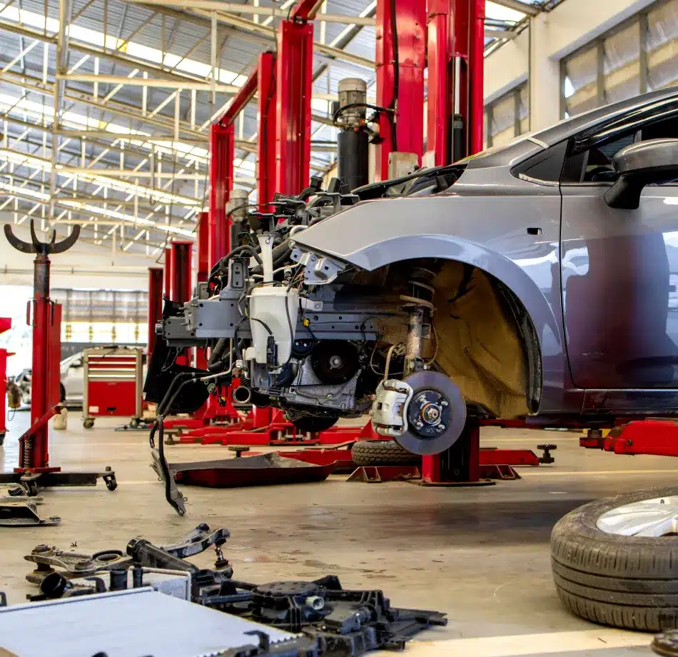 Partially disassembled car elevated on a red hydraulic lift in Cain and Sons’ Glen Rock, PA auto repair shop, highlighting expert diagnostics and repair services