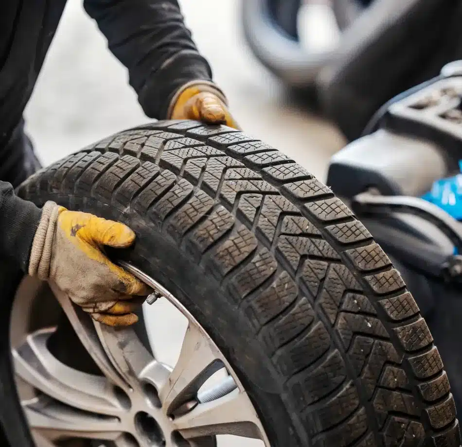 Cain and Sons’ Automotive technician in Glen Rock, PA wearing yellow gloves while installing a tire, ensuring proper fit for ADAS alignment and calibration.