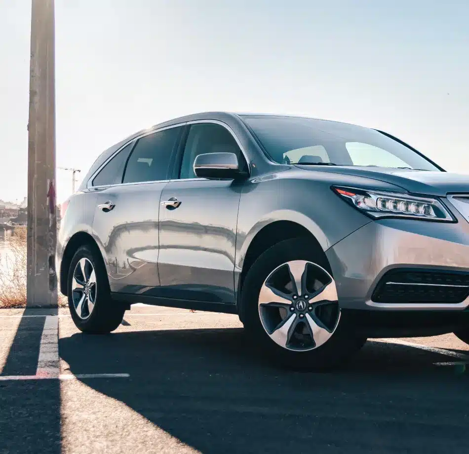 Silver SUV parked in a sunlit area, casting shadows on the ground. Clear blue sky in the background conveys a calm, sunny day.