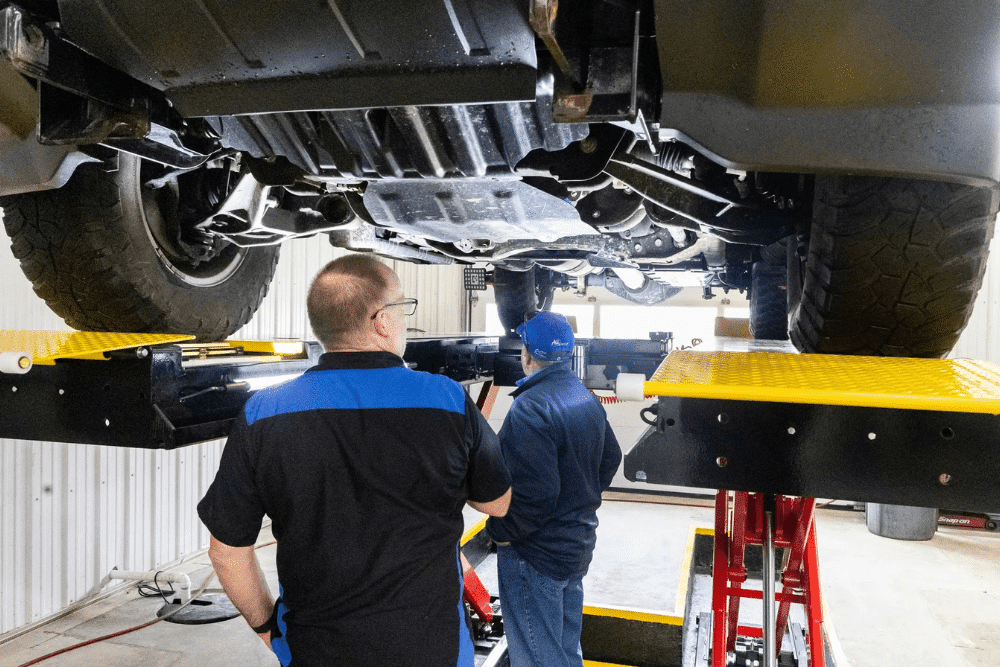 Pre-trip inspection, auto repair in Glen Rock, PA by Cain and Sons' Automotive. Image of technicians inspecting the undercarriage of a truck on a lift, highlighting thorough underbody checks for safety, suspension integrity, and overall vehicle reliability.